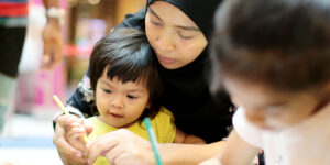 a mom helps her daughter color