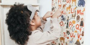 a girl looks at an alphabet poster