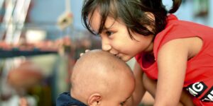 big sister kisses baby's head