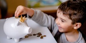 a boy puts coins in a piggy bank