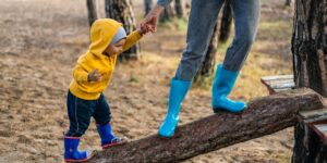 a boy balances on a log in the woods