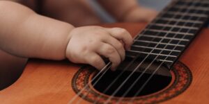 a baby hand plucks a guitar