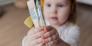 toddler holds paintbrushes