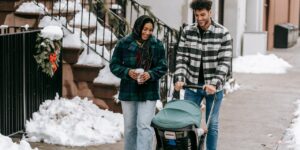 family with baby in stroller walks in neighborhood